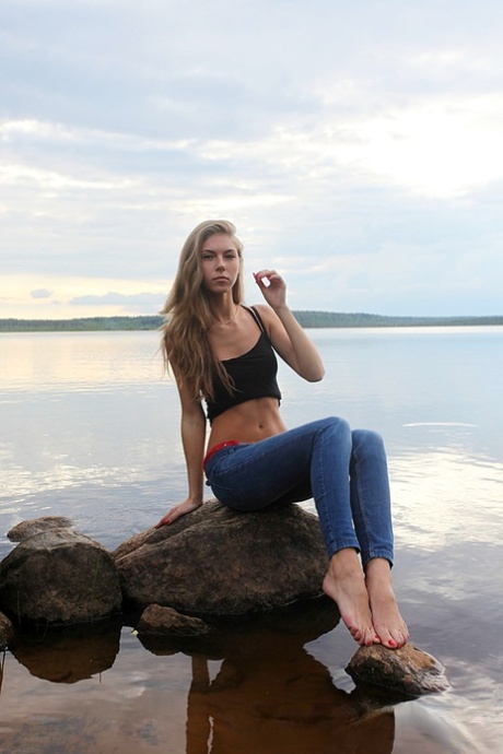 Girl next door Megan pulls out her tits while sitting on a rock in the lake