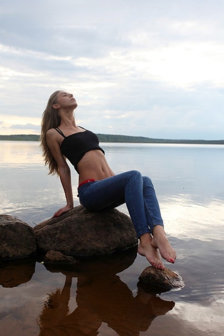 Girl next door Megan pulls out her tits while sitting on a rock in the lake