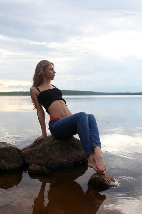 Girl next door Megan pulls out her tits while sitting on a rock in the lake