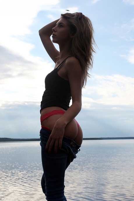 Girl next door Megan pulls out her tits while sitting on a rock in the lake