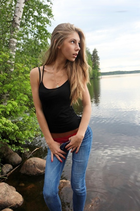 Girl next door Megan pulls out her tits while sitting on a rock in the lake