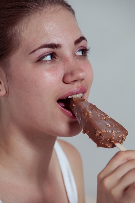 Cute teen Jasmina eats an ice-cream and strips to pose on a bed