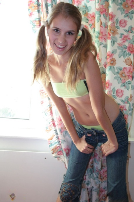 Young looking girl plays with her pigtails while stripping to her socks