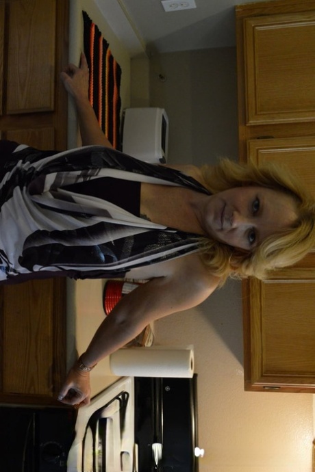 Mature blonde strips in the kitchen & rubs her juicy tits and hot pussy