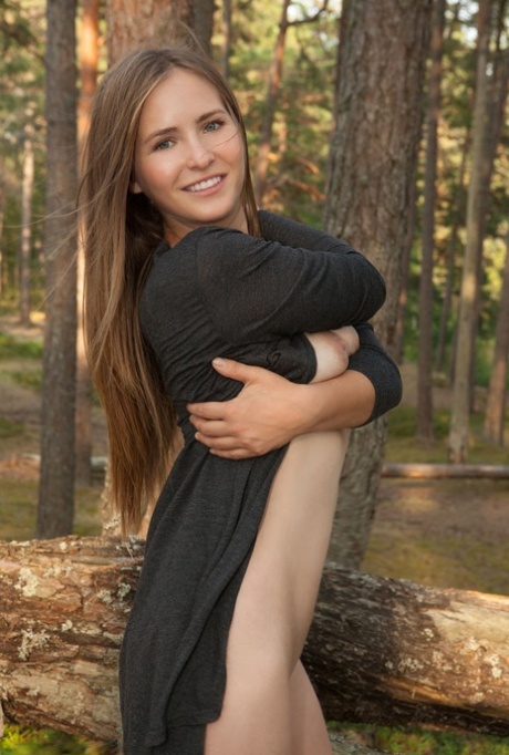 Busty teen Narina A poses totally naked on a fallen tree in a forest