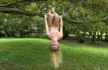 Cute blonde Emma Starletto shows off her flexibility while naked in the yard