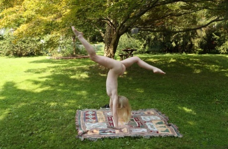 Cute blonde Emma Starletto shows off her flexibility while naked in the yard