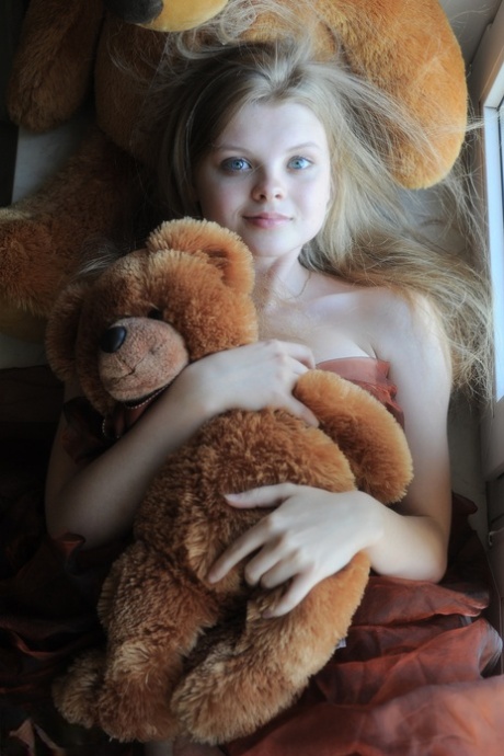 Tiny teen Kisa strikes tempting nude poses while holding a teddy bear