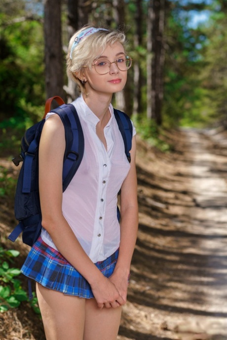 Young looking girl Azshara strips off school clothes on a dirt road in woods