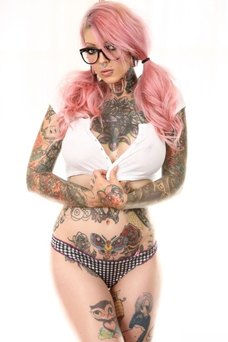 Tattooed emo babe with glasses uncovering her big fake tits and shaved cunt