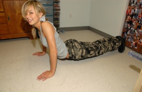 Blonde teen pulls down camo pants before having her tight ass flogged